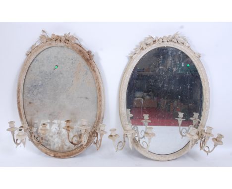 A pair of Victorian white painted and moulded overmantel mirrors, the oval plates surmounted with leaves and flower heads (wi