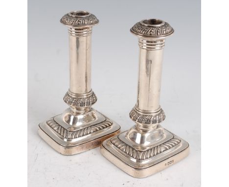 A pair of Edwardian silver table candlesticks, each having a removable sconce to a plain column and stepped and loaded rectan