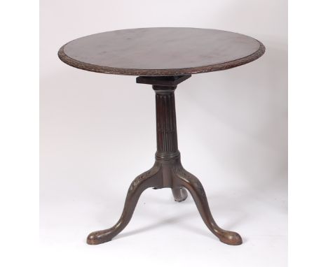 A George III mahogany pedestal tripod table, the one-piece tilt-top having a leaf and ribbon carved edge, over a stop-fluted 