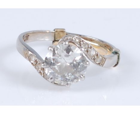 A white metal single stone diamond crossover ring, the round brilliant cut diamond in an eight claw setting, measuring approx