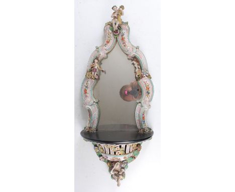 A 19th century German porcelain wall mirror, probably by Meissen, the shaped plate in a C-scroll surround surmounted with a c