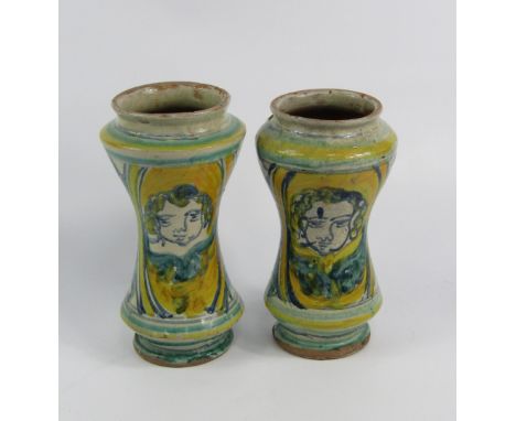 A pair of 19thC Italian pottery albarello, of waisted form painted with masks and flowers, 22cm high, (AF).