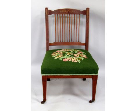 An Edwardian mahogany nursing chair, the slatted back with painted marquetry type decoration of musical trophies, leaves, flo