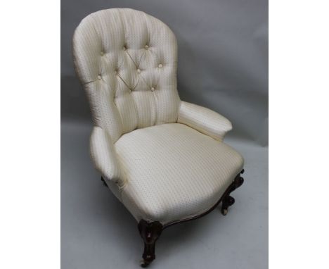 A late 19th century low seated button backed armchair, recently reupholstered in decorated antique ivory material, supported 