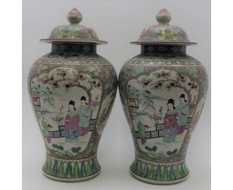 A pair of 20th century Chinese ceramic covered vases of baluster form, hand painted in the famille rose palette, featuring pa