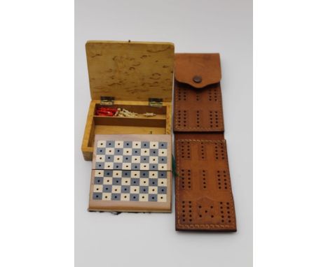 A small blonde wood box opening to reveal a miniature chess set, with a full complement of turned pieces and a folding peg bo