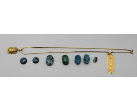An Egyptian yellow metal pendant with hieroglyph decoration, together with a yellow metal scarab pendant on a chain, and asso