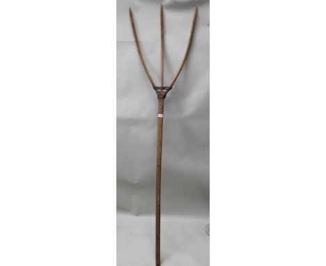 An early 20th century softwood three-pronged wooden fork, approx 182cm long 