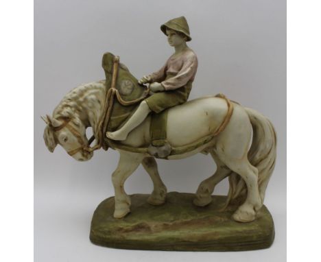 A Royal Dux ceramic figure of a harnessed cart horse being ridden by a boy, on a ground work base, under the base can be foun