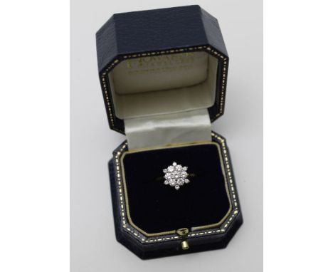 A diamond cluster ring, flower head form, brilliant cut central stone, surrounded by six diamonds with six smaller stones on 