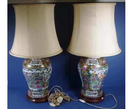 Pair Chinese tall ceramic table lamps each decorated with figures on floral ground, on wood bases. With shades. Height 45cm a
