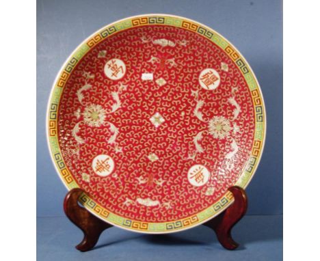 Chinese ceramic plate on stand floral and bat decoration, on burgundy ground. Character mark to base. On wood plate stand. Di
