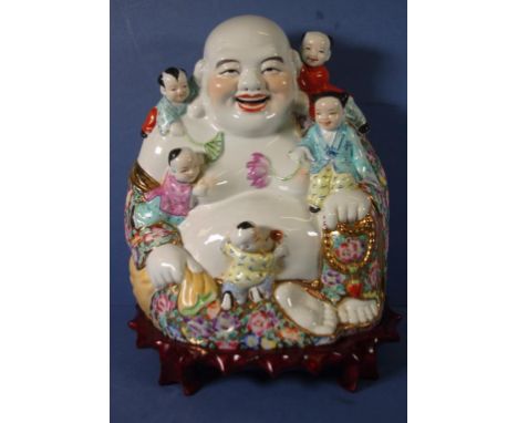 Chinese ceramic Laughing Buddha surrounded by children, on carved wood stand. Height 48cm approx (total with stand).