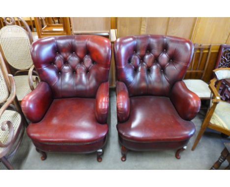 A pair of red leather button back armchairs 