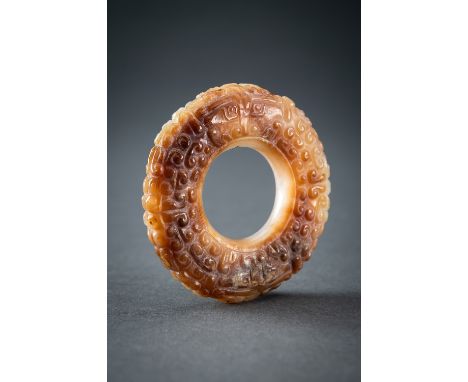 A WHITE AND RUSSET JADE 'CURLS AND TAOTIE MASKS' RING, HUAN, QINGChina, Qing Dynasty (1644-1912). Meticulously crafted in the