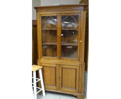 ANTIQUE LIGHT OAK STANDING CORNER CUPBOARD with two door glazed top, arch decoration and two door cupboard base, 209 x 118cms