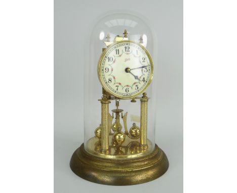 GERMAN GILT METAL ROTARY CLOCK in a glass dome with circular enamel dial by Schatz