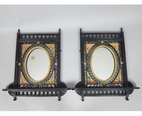 Pair of parcel gilt and ebonised framed oval mirrors with spindle turned frieze, aesthetic painted flower spandrels and shelf