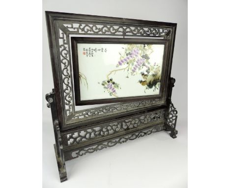 Chinese wooden table screen, with pierced scrolling decoration, the centre with a rotating porcelain plaque depicting birds a