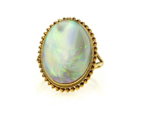 A yellow metal dress ring set with an oval opal.