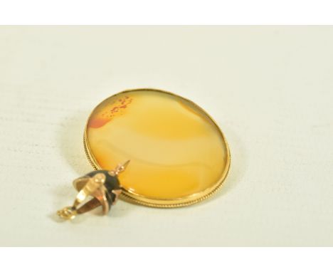 A YELLOW METAL BROOCH AND A CHARM, the first an oval shape carnelian brooch within a rope twist surround, stamped 9CT, length