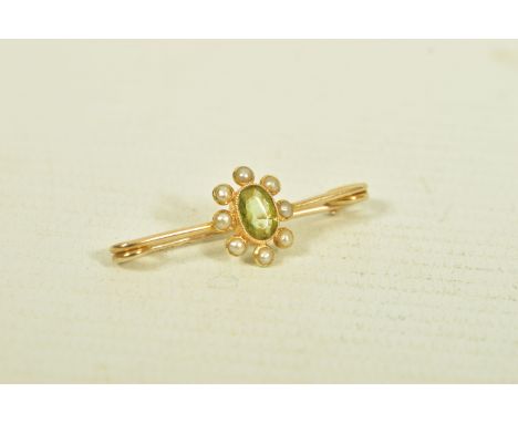 A YELLOW METAL PERIDOT AND SPLIT PEARL BAR BROOCH, the oval collet set peridot, within a split pearl cluster surround, stampe