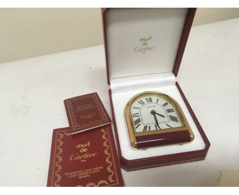 A Cartier traveling clock in a fitted case with certificate of  authenticity.