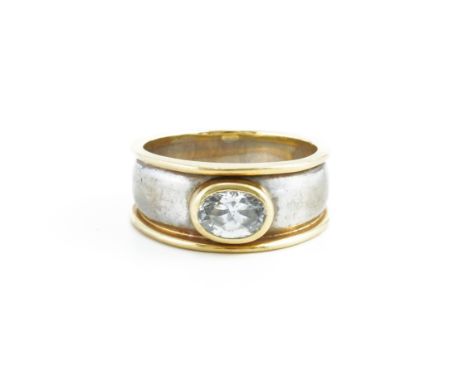 A CZ SET BICOLOUR BAND RINGWith central bezel set oval cut cubic zirconia, mounted in a unmarked bicolour band ring testing a