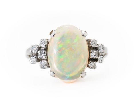 AN OPAL AND DIAMOND RINGWith central claw set oval cabochon opal measuring 12.1mm. x 5.5, flanked either side by five single 