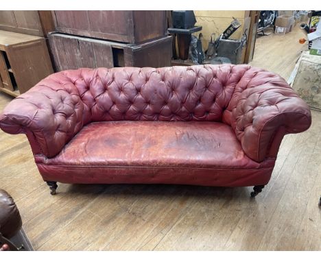 A red Chesterfield style sofa, 194 cm widenot horse hair, foam. Variation of colour, some splits and holes to the leather,