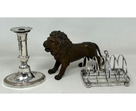 A spelter figure of a lion, 14.5 cm high, a 19th century plated on copper toast rack, and a similar candlestick (3)