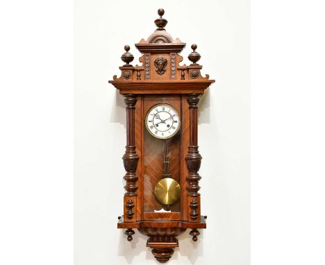 A late 19th century Vienna type wall clock, with arched pediment above mask head and enamel dial set with Roman numerals, hei