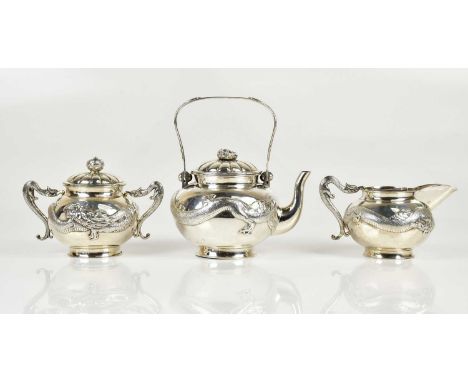 A Chinese Export silver three-piece tea service with dragon decoration, comprising lidded teapot, lidded sugar bowl and milk 