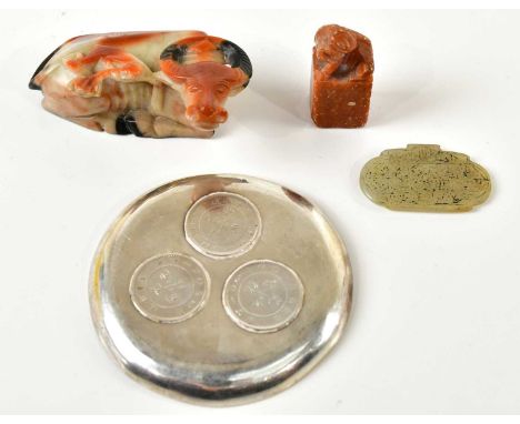 A Chinese white metal dish, inset with three Chinese coins, carved soapstone model of a cow, soapstone miniature Dog of Fo, a