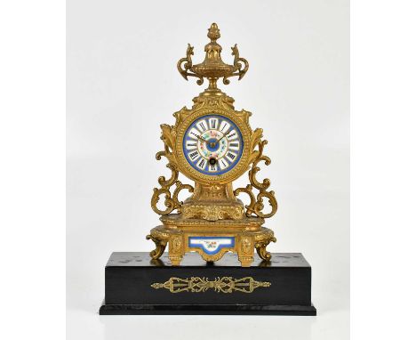 An early 20th century gilt metal mantel clock, with urn finial above the porcelain dial set with Roman numerals and floral de