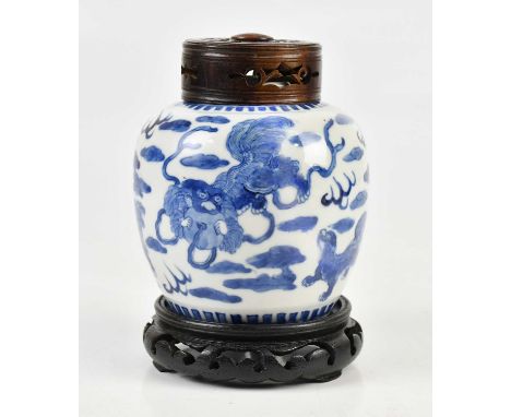 A late 19th century Chinese blue and white ginger jar with associated carved wooden cover and stand, decorated with Dogs of F