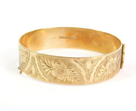 A 9ct gold bangle, with all over etched design of flowers and leaves, weighted, of hinged form with safety chain, 31.6g all i