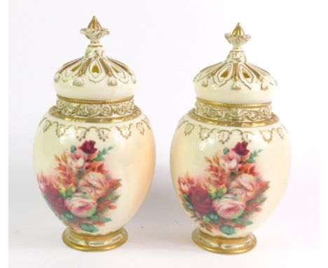 A pair of Royal Worcester style porcelain pot pourri vases and covers, decorated with roses against a blush ground, of balust