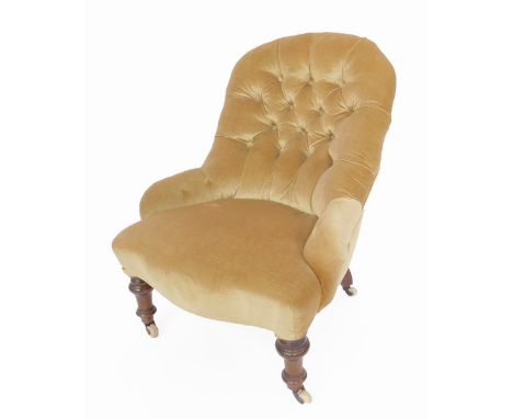 A Victorian oak nursing chair, upholstered in gold button back draylon and overstuffed serpentine seat, raised on turned legs