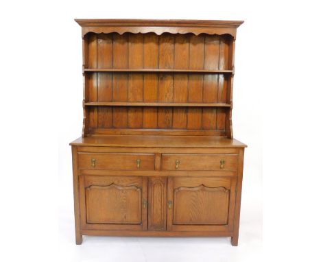 A Georgian style oak dresser, with a two shelf plate rack over two drawers above panelled cupboard doors, raised on square le