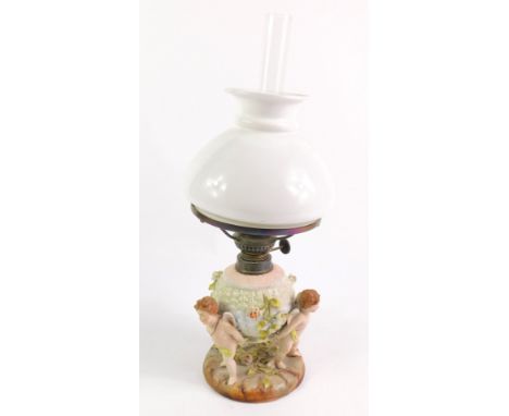 A German early 20thC Sitzendorf style porcelain oil lamp, of globular basket form raised on three cherub supports on a circul