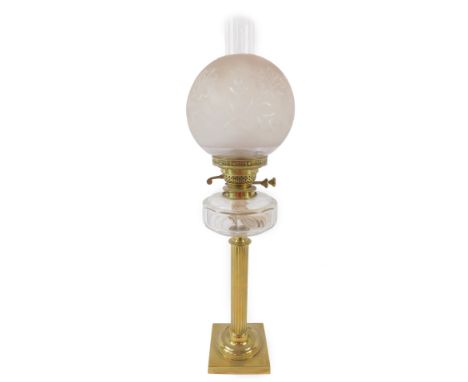 A brass early 20thC fluted column oil lamp, with a cut glass reservoir, raised on a square base with chimney and etched globu