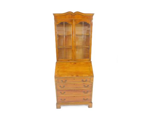 A Georgian style yew wood and cross banded bureau bookcase, the pediment over two glazed doors, enclosing two shelves, over a