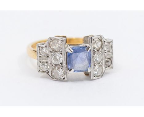 An Art Deco sapphire and diamond 18ct gold ring, comprising a claw set pale blue cushion cut sapphire, within a double row of