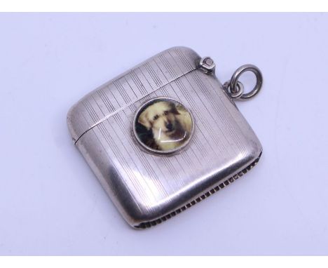A George V silver novelty vesta case, striated pattern, the centre inset with roundel portrait of a Dog (Spaniel), on suspens