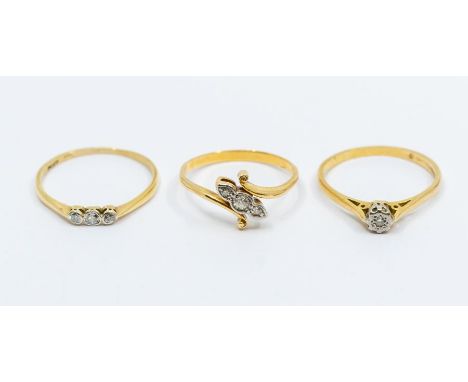 A diamond set yellow metal ring, comprising three graduated diamonds with a cross over scroll mount, size size R, assessed as