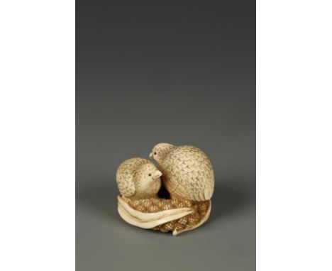 A JAPANESE IVORY QUAIL NETSUKE, the two birds facing in opposite directions and standing on millet, with inlaid eyes, signed 