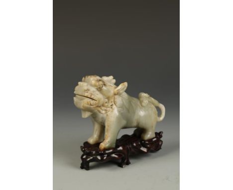 A CHINESE CELADON JADE CARVING OF A MYTHICAL BEAST, the lion-like creature standing with its' head raised, late Qing, 6" long