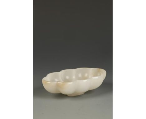 A CHINESE PALE CELADON JADE EIGHT-LOBED VESSEL, the oval form suggesting a flower, the translucent stone with some russet mar