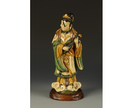 A CHINESE 'TILEMAKERS' FIGURE OF A FEMALE IMMORTAL decorated in sancai glazes and standing upright playing a stringed instrum
